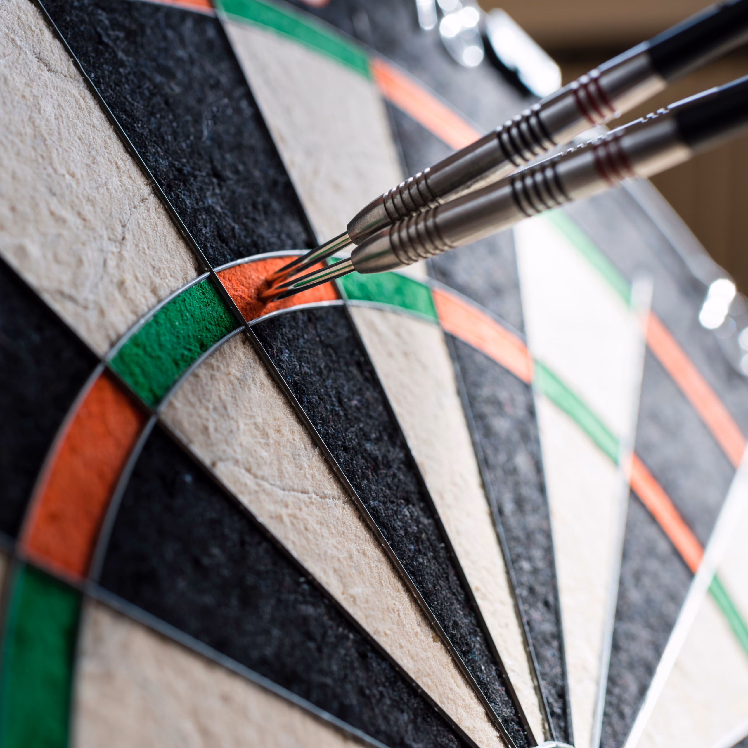 Nahansicht zweier feststeckender Dart-Pfeile in einer Dartscheibe.