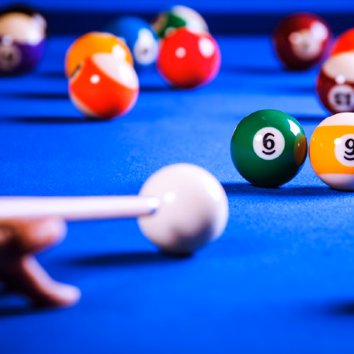 Nahansicht eines Pool Billardtisches und einer spielenden Person, die auf die weiße Kugel zielt